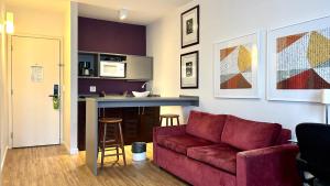 a living room with a red couch and a kitchen at QSA - Anora Spaces - Metropolis Alphaville in Barueri