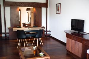 uma sala de estar com uma mesa e cadeiras e uma televisão em Manava Beach Resort & Spa Moorea em Maharepa