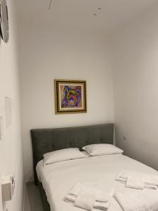 een bed in een witte kamer met een foto aan de muur bij B&B Kemare Suites in Barletta