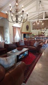 a living room with leather furniture and a chandelier at Hartland Country House Oudtshoorn in Oudtshoorn
