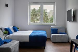 - une chambre avec un lit, une fenêtre et une chaise dans l'établissement Top Loft Znana, à Varsovie