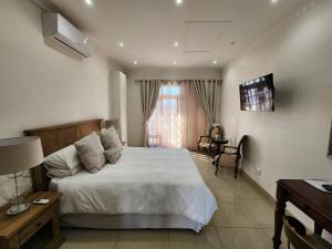 a bedroom with a bed and a desk and a television at Villa Marche in Van Riebeekhoogte