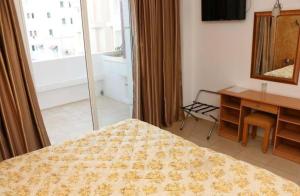 1 dormitorio con cama, escritorio y ventana en Hotel yasmine en Sfax