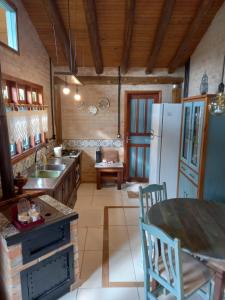 eine Küche mit einem Tisch und einem Kühlschrank in der Unterkunft Pousada Bosque das Águas, Imbituba in Barra de Ibiraquera