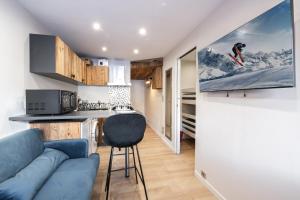 a living room with a blue couch and a kitchen at Appartement 2 chambres avec balcon et parking in Val Thorens