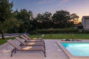 a row of lounge chairs next to a swimming pool at Villa Valma by IstriaLux in Svetvinčenat
