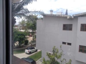 une voiture blanche garée dans un parking à côté d'un bâtiment blanc dans l'établissement Hospedaria U, à Lobito