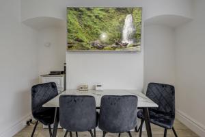 een eettafel met stoelen en een watervalschilderij aan de muur bij Ridge Grove Lodge "Sleeping 4 guests" 
