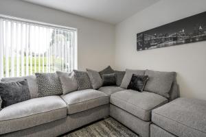 a gray couch in a living room with a window at Ridge Grove Lodge "Sleeping 4 guests" 