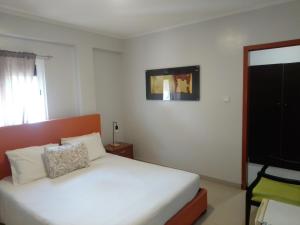 LobitoにあるHospedaria Uのベッドルーム(白いベッド1台、壁掛けテレビ付)