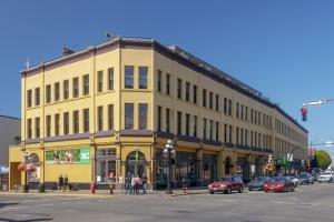 a large yellow building on a city street with cars at Modern Heritage Studio With Murphy Bed in Victoria