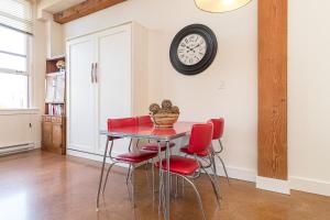 a dining room table with red chairs and a clock on the wall at Modern Heritage Studio With Murphy Bed in Victoria +16 photos