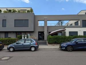 2 voitures garées sur un parking en face d'un immeuble dans l'établissement 1 Bedroom Apartment with Garage & Outdoor Area in Kirchberg, à Luxembourg