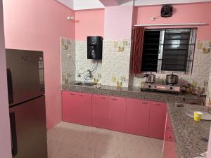 a kitchen with pink cabinets and a refrigerator at Sneha’s Happy Home. in Guwahati