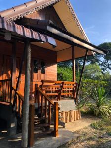 Casa con porche con bancos de madera en la parte delantera en Lampang homestay2, en Lampang