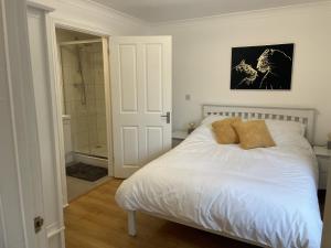 um quarto com uma cama branca e um chuveiro em Modern The Mews Apartment em Bury Saint Edmunds