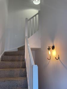 a staircase with a white wall and a light at Modern The Mews Apartment in Bury Saint Edmunds