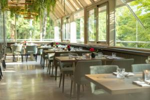 a dining room with tables and chairs and windows at Parkhotel Schmid in Adelsried