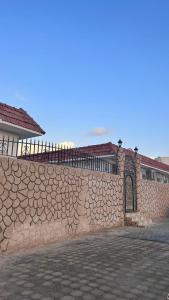 a stone wall with a gate in front of a house at Farm dream in Al Rahba