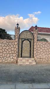 a stone fence with a gate in front of a house at Farm dream in Al Rahba