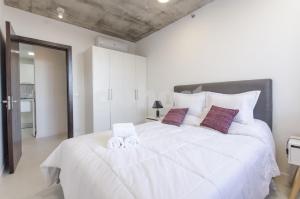 1 dormitorio con 1 cama blanca grande y 2 toallas en Modern 1 Bedroom Apt Near Shopping Del Sol, en Asunción