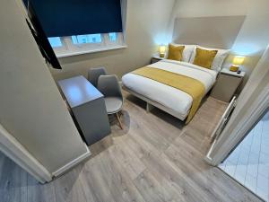 um quarto de hotel com uma cama, uma secretária e uma cadeira em BOKA Earls Court em Londres