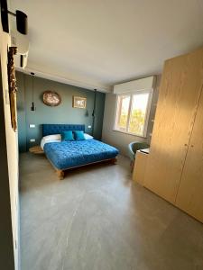 Un dormitorio con una cama azul y una ventana en OliVia Rooms Sauna & Gym en Forlì