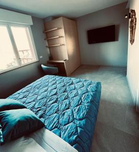 um quarto com uma cama azul e uma televisão em OliVia Rooms Sauna & Gym em Forlì