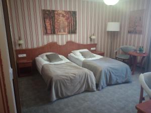 ポズナンにあるBiały Dom Henlex Hotel Restauracjaのベッド2台とテーブルが備わるホテルルームです。