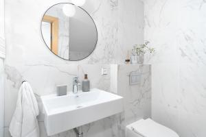 ein weißes Badezimmer mit einem Waschbecken und einem Spiegel in der Unterkunft Maisonette Apartment in Karlín by Prague Days in Prag
