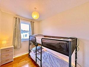 a bedroom with two bunk beds and a window at Kanangra, 2 bedroom apartment in Teignmouth in Teignmouth
