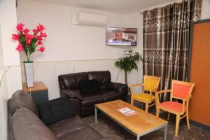 a living room with a leather couch and chairs at Hotel le Privilege in La Courneuve