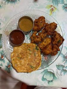 a plate of food with chicken wings and dipping sauces at Season homestay in Kathmandu