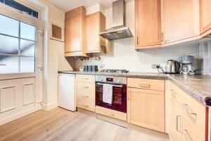 a kitchen with wooden cabinets and a stove top oven at Free Parking Charming Private Apt in Perivale