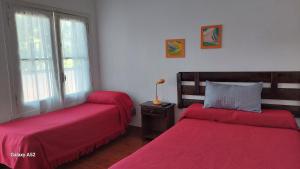 two beds in a room with red sheets at Hostería Almirante Brown in Mar del Plata