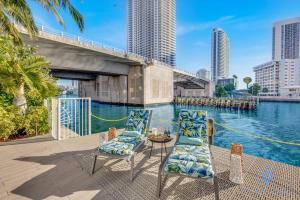 a patio with chairs and a table next to a body of water at Infinite View Balcony - Amazing Pool - Gym in Hallandale Beach