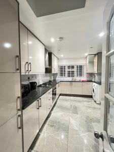een keuken met witte kasten en een tegelvloer bij StayEasy En-Suite London in Londen