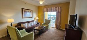 Best Disney Resort Condo Orlando في أورلاندو: غرفة معيشة مع أريكة وكراسي وتلفزيون