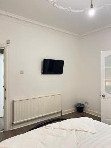 een slaapkamer met een tv aan een witte muur bij StayEasy En-Suite London in Londen