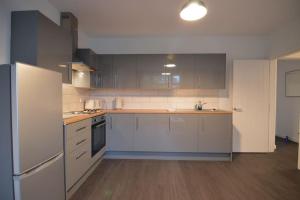 a kitchen with white cabinets and a white refrigerator at Contemporary 3 Bedroom Flat in Fife
