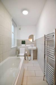 a white bathroom with a tub and a sink at Contemporary 3 Bedroom Flat in Fife