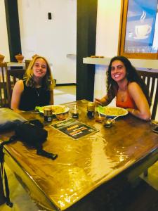 迪克韋勒的住宿－Hiriketiya New Radiant House，两个坐在餐桌上,配上食物盘的女人