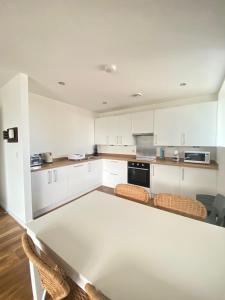eine Küche mit weißen Schränken und einem Tisch in der Unterkunft En-suite Private Room in Manchester