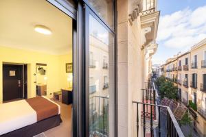 une chambre avec un balcon avec un lit et une vue dans l'établissement Hostal Ballesta, à Madrid 117 autres photos