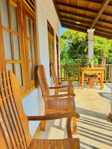 three wooden chairs sitting on the porch of a house at lake paradise in Habaraduwa
