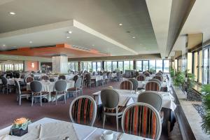 a restaurant with white tables and chairs and windows at Hotel Solverde Spa and Wellness Center in Vila Nova de Gaia