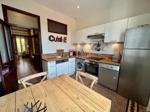 a kitchen with a table and a stainless steel refrigerator at L'Annexe Apparthôtel Porto Vecchio, 4 étoiles in Porto-Vecchio