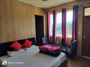 a bedroom with a bed with red pillows and a window at Silver Dew Resorts and Restaurant in Dhanaulti