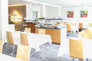 ein Restaurant mit weißen Tischen und Stühlen und einer Theke in der Unterkunft Hotel Ambiente in Münster
