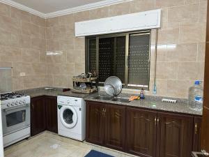 a kitchen with a sink and a washing machine at شقه للأيجار في منطقه الراهبات الورديه in Irbid